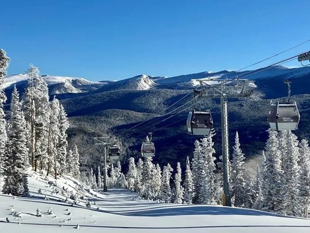 A dynamic winter landscape showing gondolas gliding above snowy slopes lined with evergreens, against a backdrop of rugged mountain scenery. The image exudes excitement and the promise of alpine sports such as skiing and snowboarding.