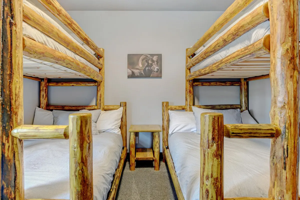 A playful and inviting room featuring sturdy wooden bunk beds, cheerful bedding, and wall artwork. The space is designed for family fun, accommodating groups or children with a cozy, communal vibe.