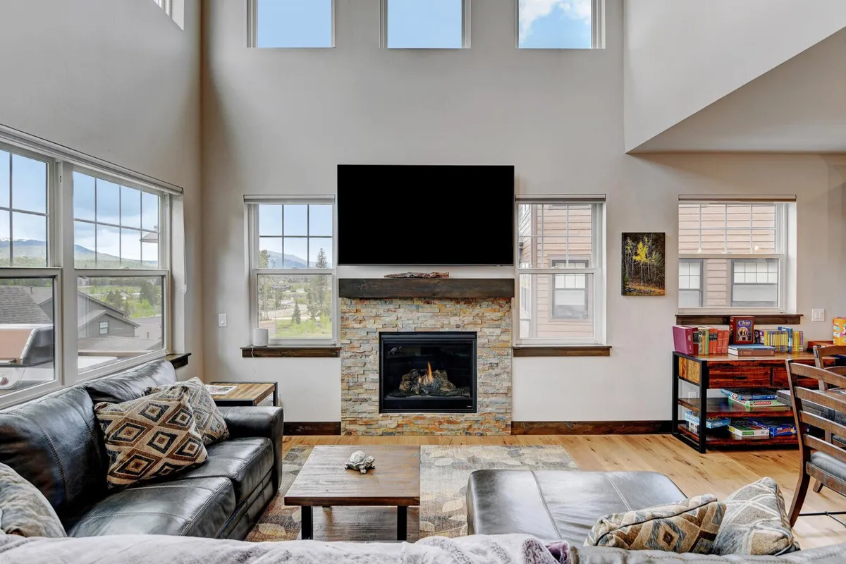 A warm, inviting secondary living area with a comfortable sofa, entertainment center featuring a large television, a fireplace, and expansive windows. The scene captures a space ideal for movie nights, games, or quiet relaxation.